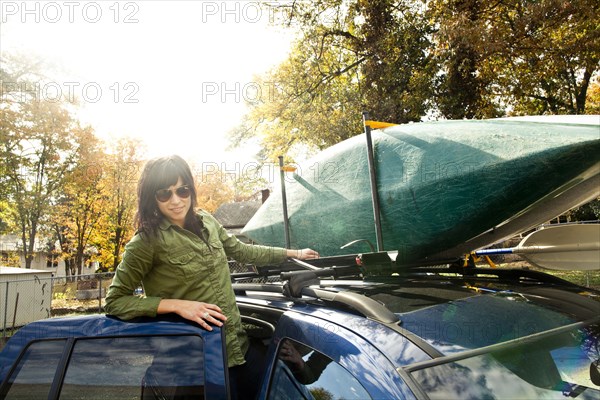 Caucasian woman packing kayak on car