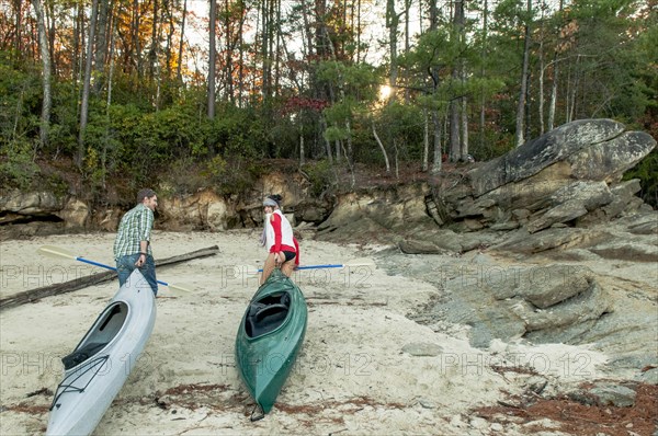 Couple pulling kayaks on rocks