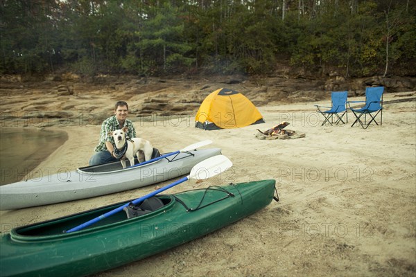Man and dog with kayak at campsite