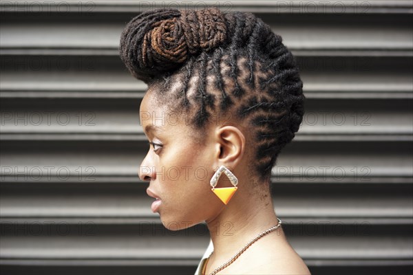 Profile of African American woman with braids near metal wall