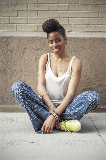 Smiling African American woman sitting on sidewalk