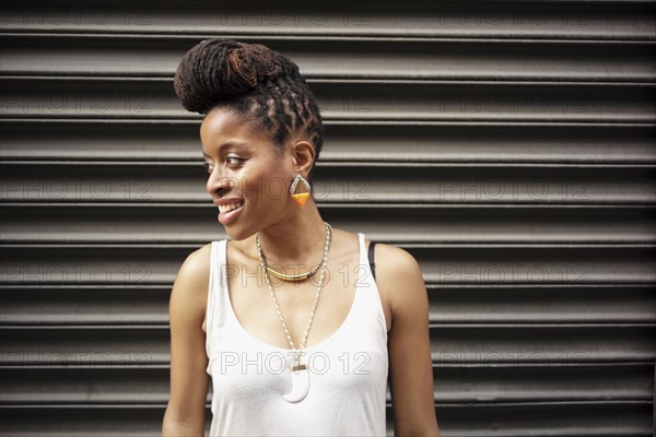 Portrait of smiling  of African American woman with braids near metal wall