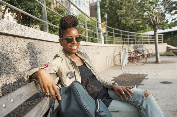 Smiling African American woman sitting on bench at park