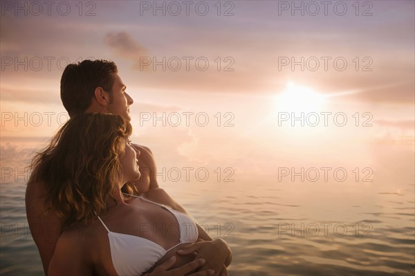 Caucasian couple admiring sunset over ocean