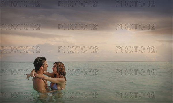 Caucasian couple swimming and hugging in ocean