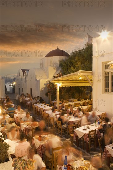 Time lapse view of tourists eating in sidewalk cafe at sunset