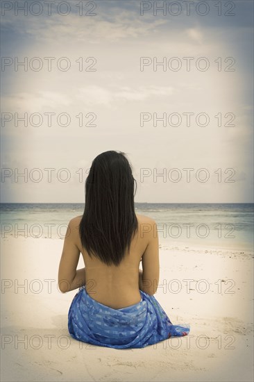 Chinese woman sitting on tropical beach