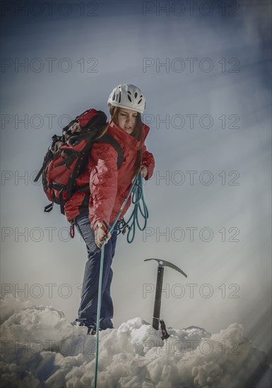 Caucasian hiker pulling rope on snowy mountaintop