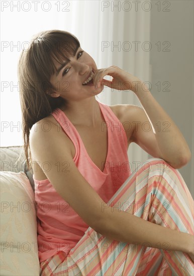 Caucasian woman wearing pajamas smiling on sofa