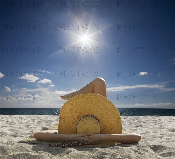 Caucasian woman relaxing on beach under blue sky