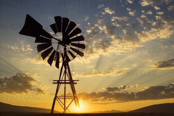 Silhouette of windmill under dramatic sunset sky