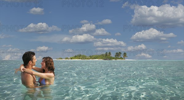 Caucasian couple hugging in tropical ocean