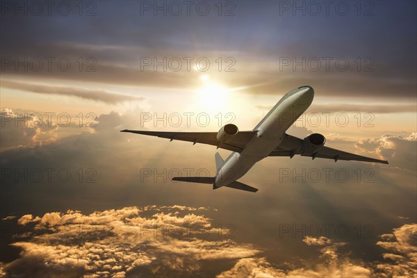 Airplane flying in dramatic sunset sky