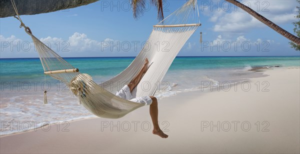 Caucasian woman laying in hammock on tropical beach