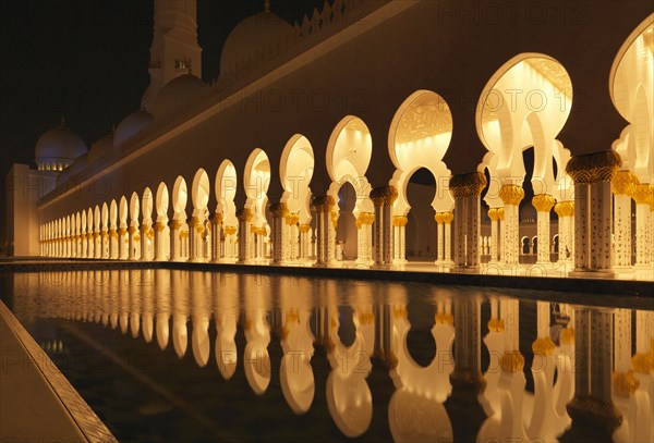 Illuminated colonnade reflecting in still pool