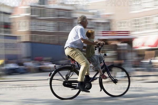 Blurred view of father and son bicycling on city street