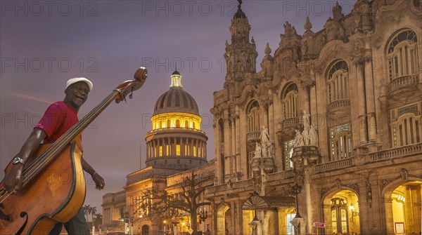 Hispanic musician carrying upright bass in city