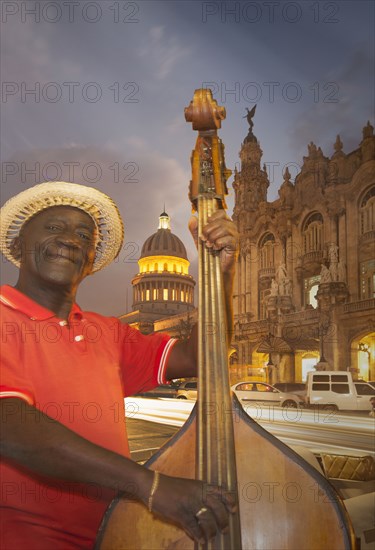 Hispanic musician playing upright bass in city