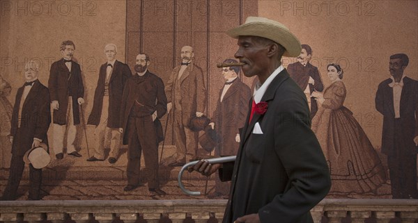 Hispanic man walking past mural