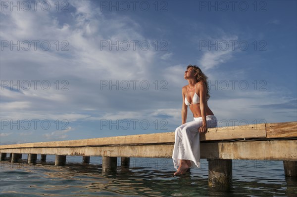 Caucasian woman sitting on wooden dock
