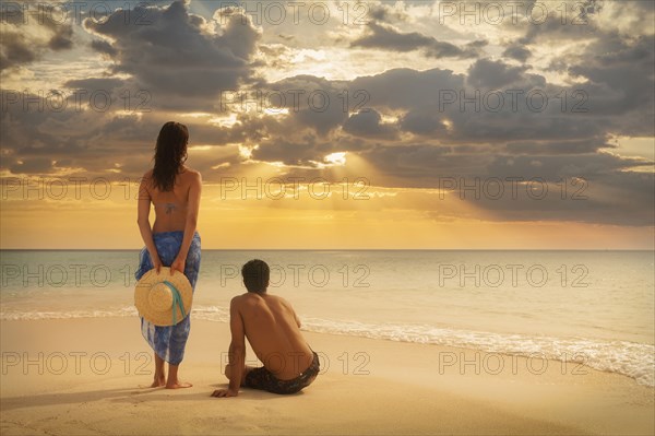 Caucasian couple admiring sunset on beach