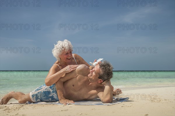 Older Caucasian couple relaxing on beach