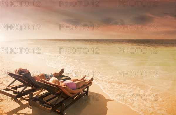 Older Caucasian couple relaxing on beach at sunset