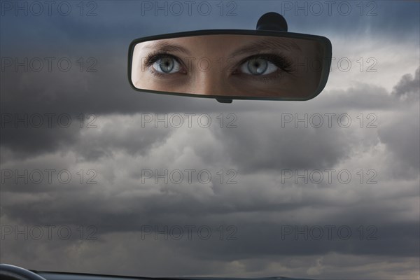 Eyes of Caucasian woman reflecting in rear view mirror