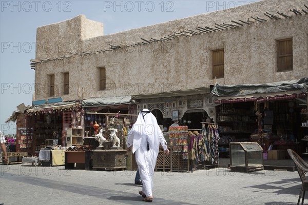 Man walking outside market on Doha sidewalk