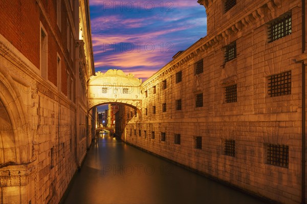 Bridge over Venice canal under sunset sky