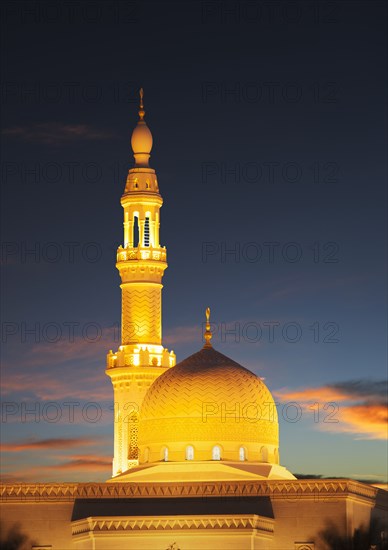 Illuminated pillar and dome under sunset sky