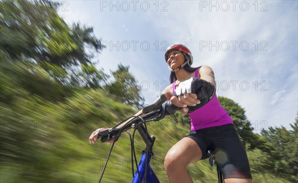 Hispanic woman riding bicycle outdoors