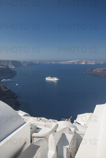 Hillside buildings over cruise ship in Santorini bay