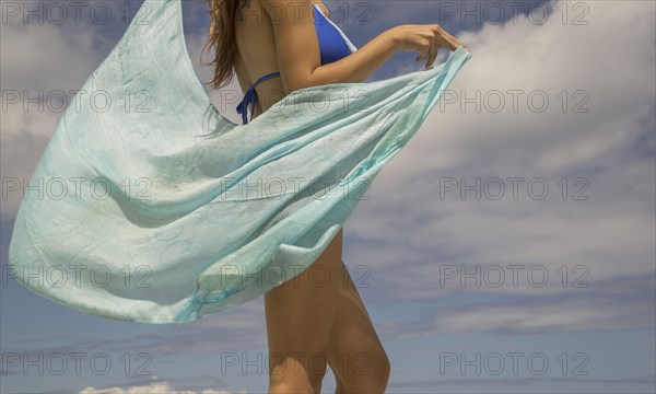 Hispanic woman holding sarong blowing in wind