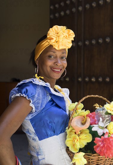 Hispanic woman carrying basket of flowers