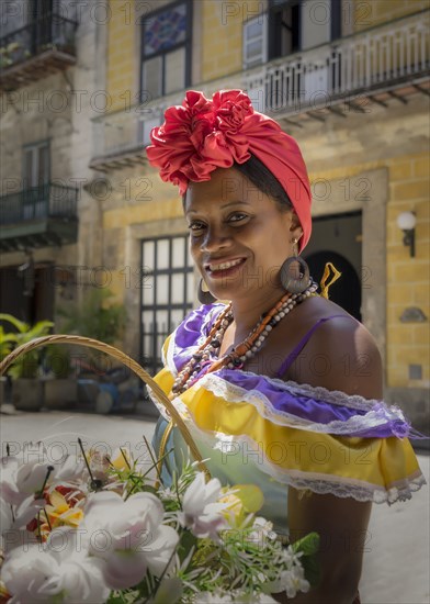 Hispanic woman carrying basket of flowers