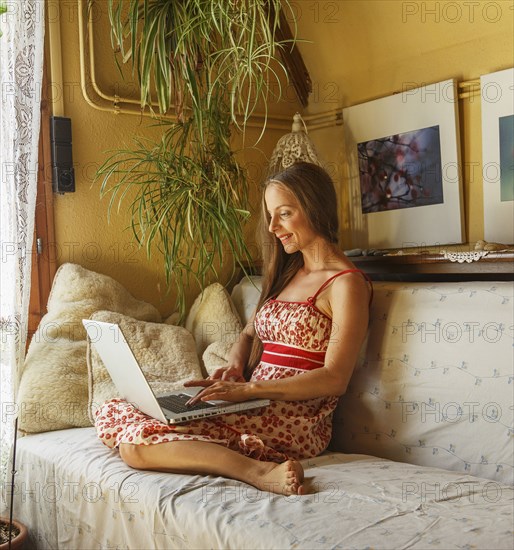 Caucasian woman using laptop on sofa