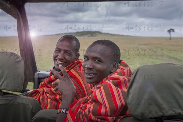 Black men smiling in car in remote field