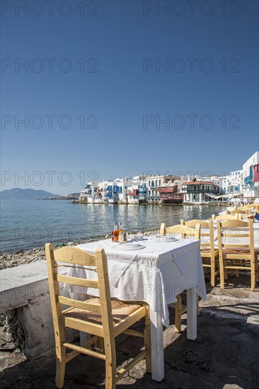 Tables at waterfront cafe under blue sky