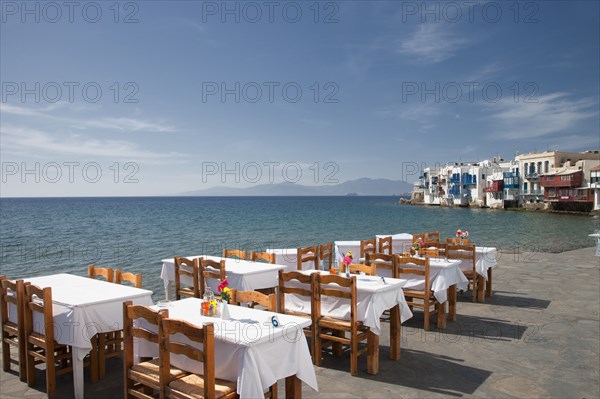 Tables at waterfront cafe under blue sky