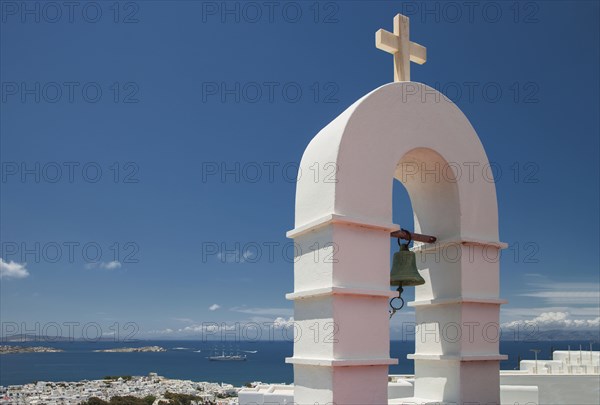 Bell arch and Mykonos cityscape under blue sky