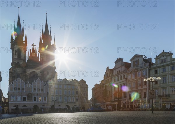 Sun shining behind ornate church in city square