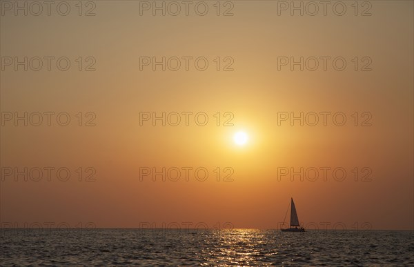 Sailboat sailing on ocean horizon at sunset