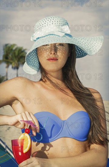 Caucasian woman drinking cocktail at beach