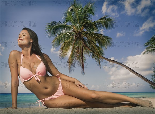 Caucasian woman in pink bikini near palm tree at beach