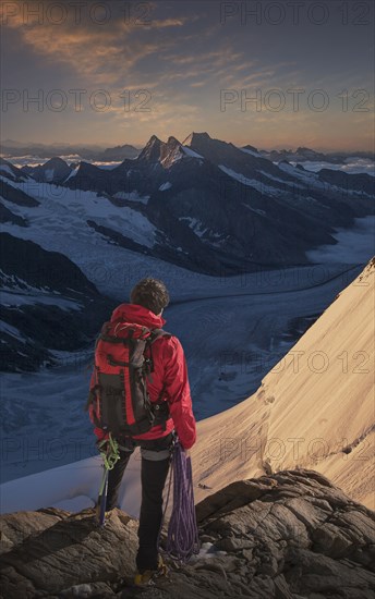 Caucasian man admiring mountain range holding climbing rope