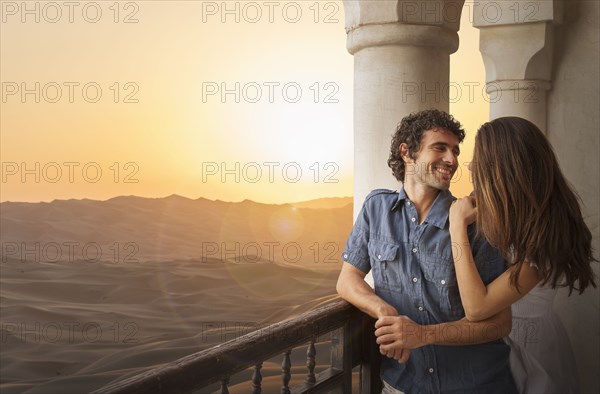 Smiling Caucasian couple on balcony in desert