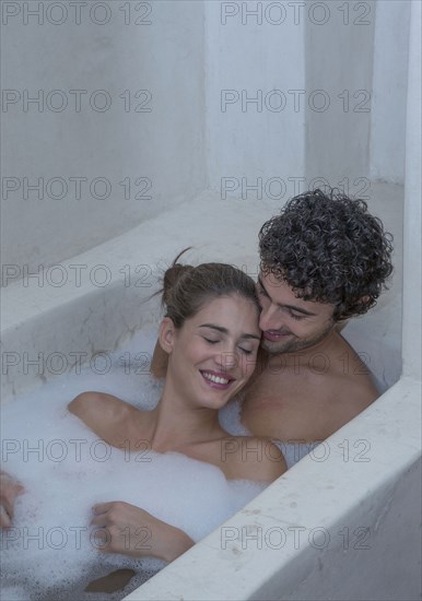 Smiling Caucasian couple relaxing in bathtub