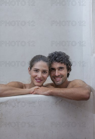 Smiling Caucasian couple relaxing in bathtub
