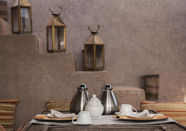 Coffee pots and plate at table near staircase